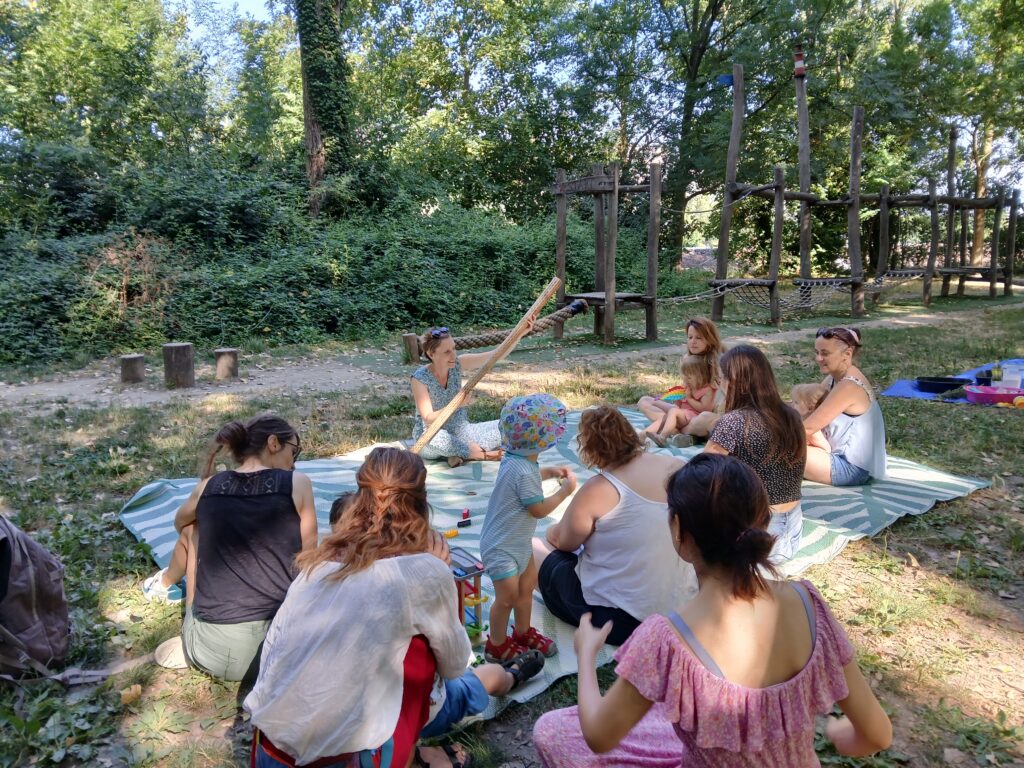 Aurore anime un atelier parents-enfants, avec plusieurs familles, dans un parc à valence