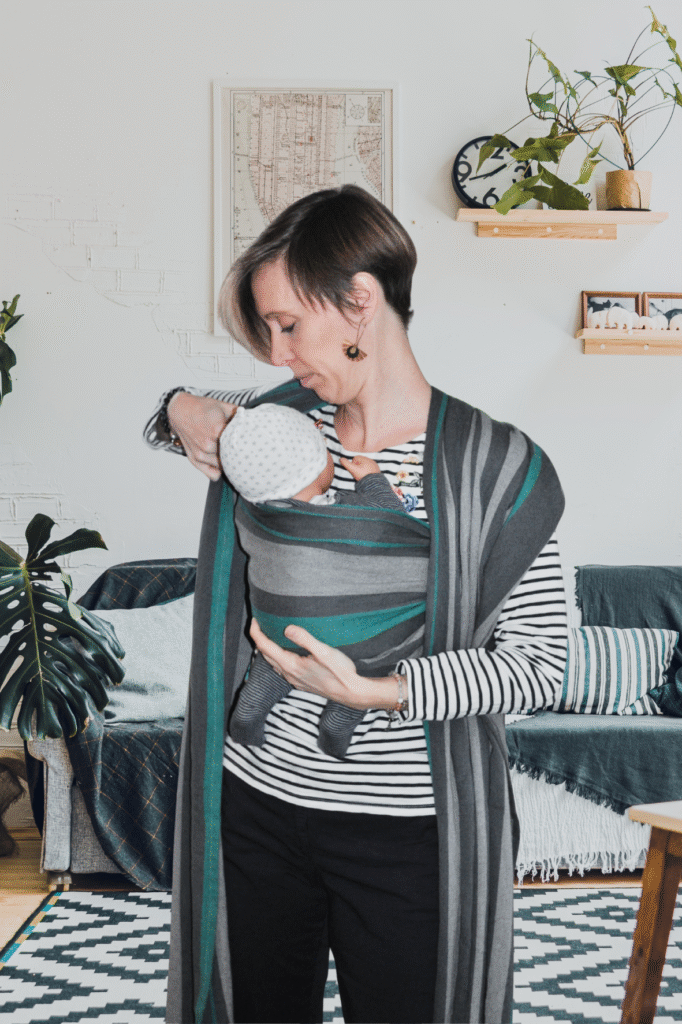Aurore installe un poupon dans une écharpe de portage lors d’un atelier de portage à Valence, montrant une gestuelle précise, sereine et bienveillante pour guider les parents pas à pas.