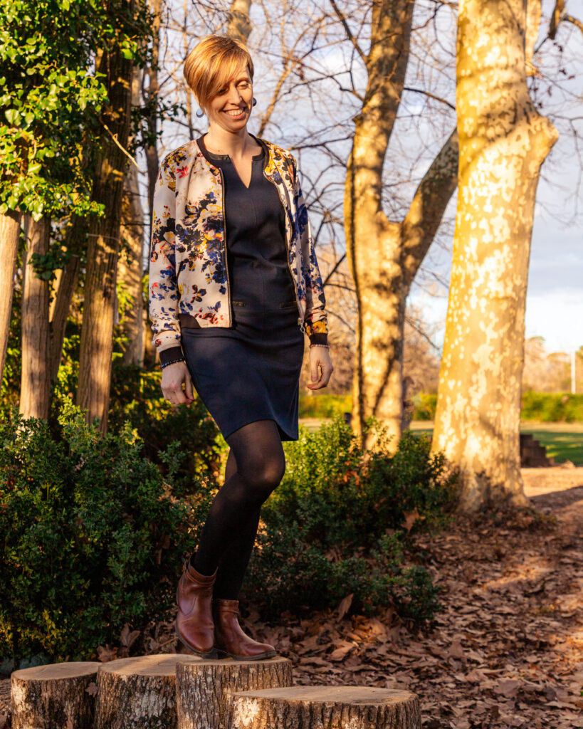 Aurore marche dans un bois en souriant, incarnant un postnatal serein et un accompagnement postpartum chaleureux