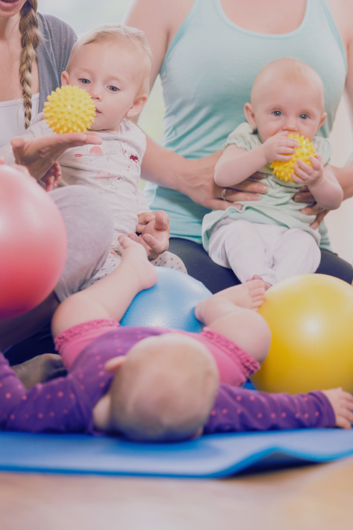 bébés qui jouent avec des balles sensorielles, entourés de professionnels de la petite enfance.