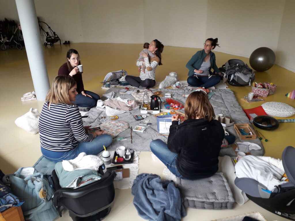 des mamans discutent ensemble et se soutiennent dans leur postpartum, tout en s'occupant de leurs bébés