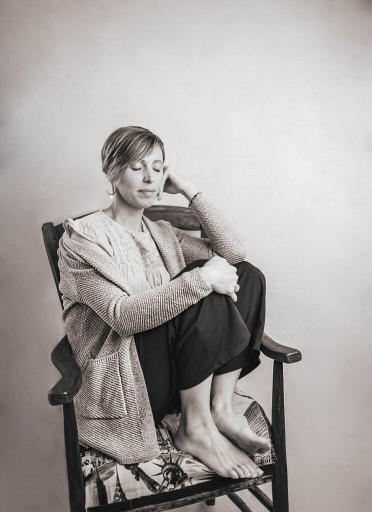 Aurore Mondelin assise dans un fauteuil, les yeux fermés, incarnant une approche sereine de l'accompagnement postnatal à Valence.